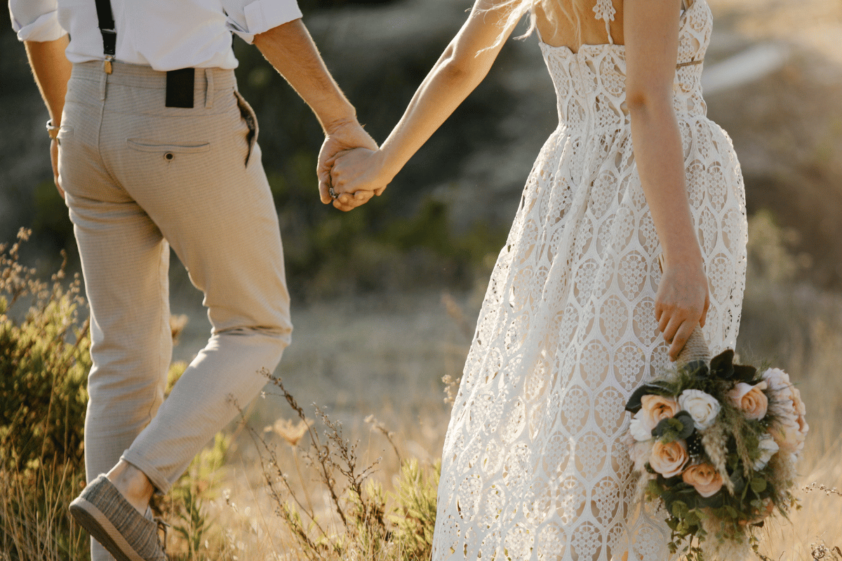 Bride and groom walk together in field
