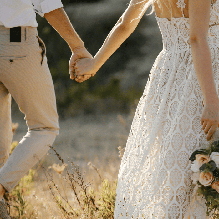 Bride and groom walk together in field