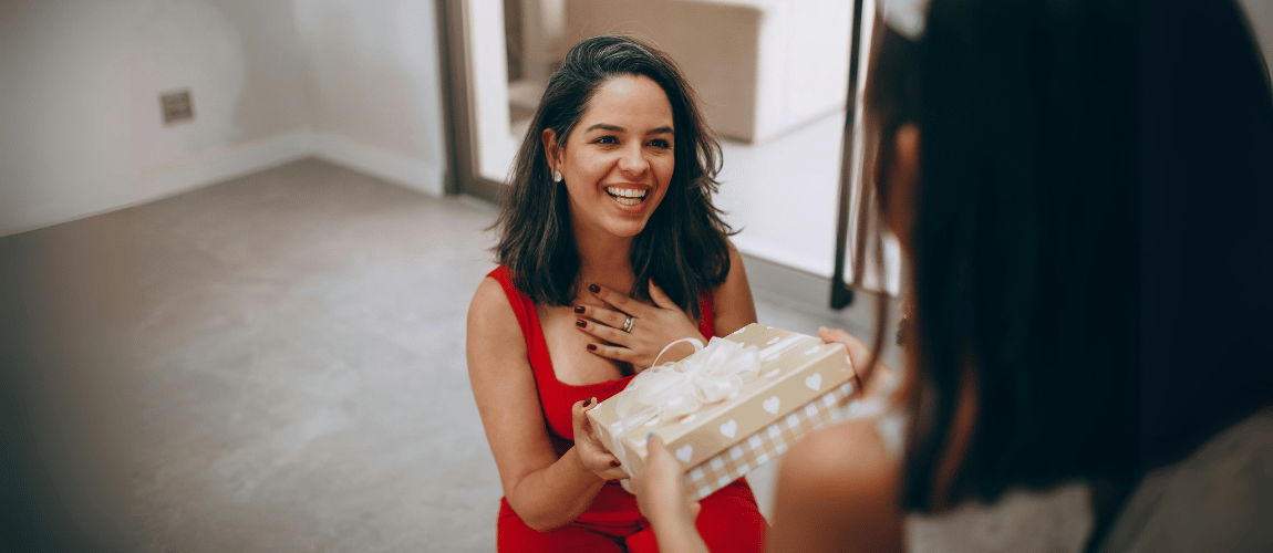 Girl hands Christmas gift to mother
