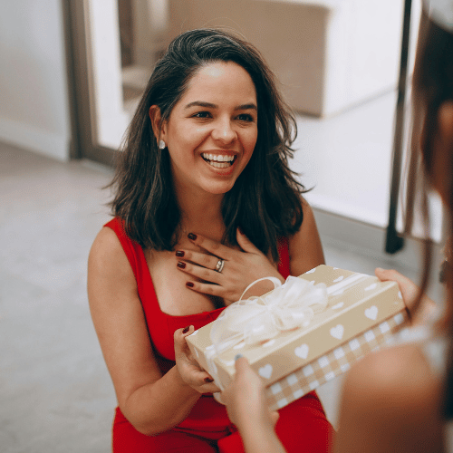 Girl hands Christmas gift to mother