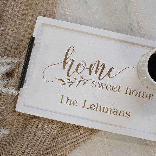 White serving tray with "home sweet home" engraved on it with a coffee mug on top