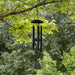 Black wind chime hanging from a tree branch with a green leafy background featuring a custom sail for retirement congratulations