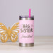 Pink tumbler with 'Big Sister' personalization and soft straw, next to a yellow butterfly decoration on a light gray background