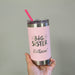 Pink tumbler with 'Big Sister' text held by a hand against a neutral background