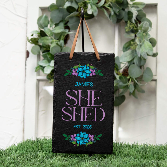 Personalized 'She Shed' sign with floral designs on a grassy background