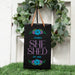 Personalized 'She Shed' sign with floral designs on a grassy background