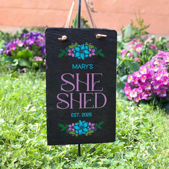 Personalized 'She Shed' sign with floral designs in a garden setting