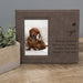 gray leather photo frame with a dog picture and text on a wooden surface.