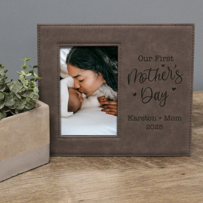 Personalized photo frame with a picture of a woman and child, text 'Our First Mother's Day' and names, on a wooden surface.