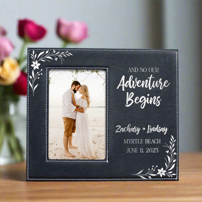Personalized photo frame with a couple on a beach and engraved text, placed on a wooden surface with flowers in the background.