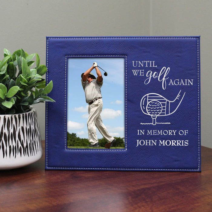 Blue photo frame with a golf-themed message on a wooden surface with a plant.
