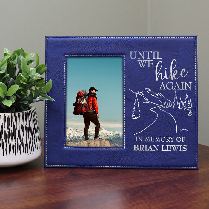 Blue photo frame with a picture of a hiker and engraved text on a wooden surface.