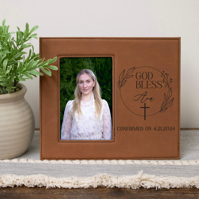 Brown leather photo frame with engraved text and a photo of a young woman, placed on a surface with a plant in the background.