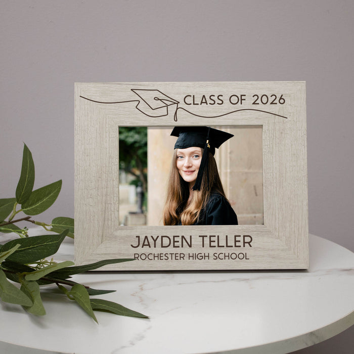 Graduation-themed photo frame with a personalized engraving on a white surface.