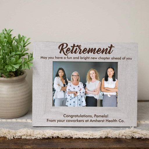 Personalized retirement photo frame with a picture of four women and a message from coworkers on a wooden surface.