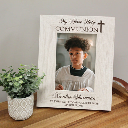 Personalized 'My First Holy Communion' frame with a photo of a young boy on a wooden surface.