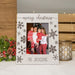 A personalized white wooden Christmas picture frame with brown snowflake designs and 'merry christmas' script, holding a family photo, styled on a white surface with holiday greenery and a candle holder.