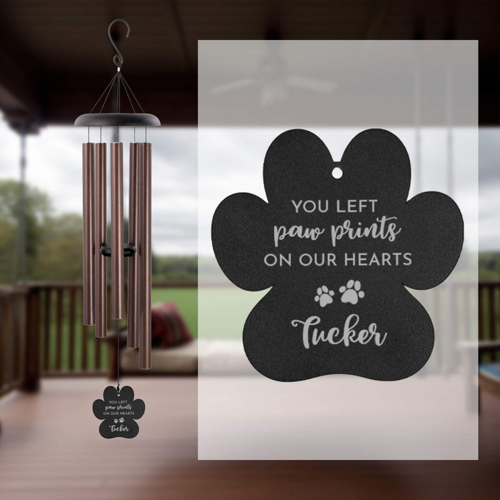Wind chime with a personalized paw print design, set against a blurred outdoor background.
