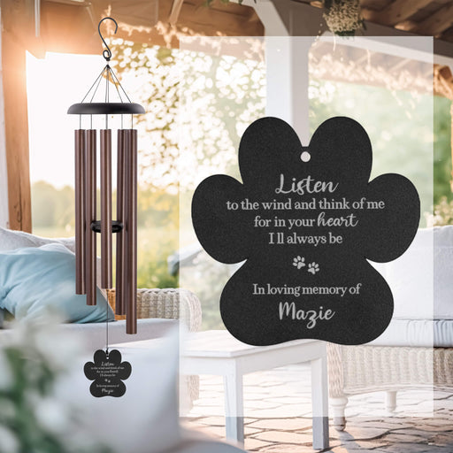 Memorial wind chime with a black paw-shaped sail in an outdoor setting.