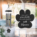 Decorative wind chime with a paw print-shaped sail in an outdoor setting.