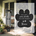 Black paw print-shaped sail with text and a wind chime on a porch.