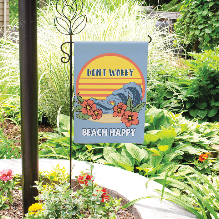 Garden flag with 'Don't Worry, Beach Happy' text and wave design in a garden setting.