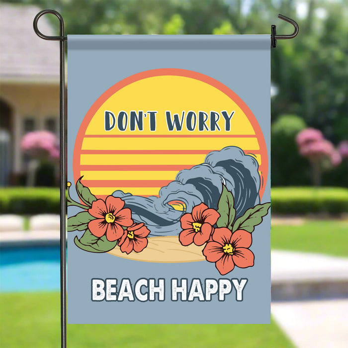 Decorative garden flag with 'Don't Worry, Beach Happy' text and floral design on a stake by the pool.