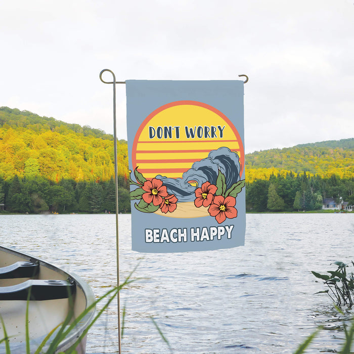 summer garden flag with a 'Don't worry, beach happy' design placed in front of a lake