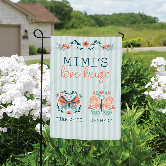 spring time garden flag for mom that says "MIMI'S love bugs" and has two butterflies printed underneath with white flowers and a house in the background