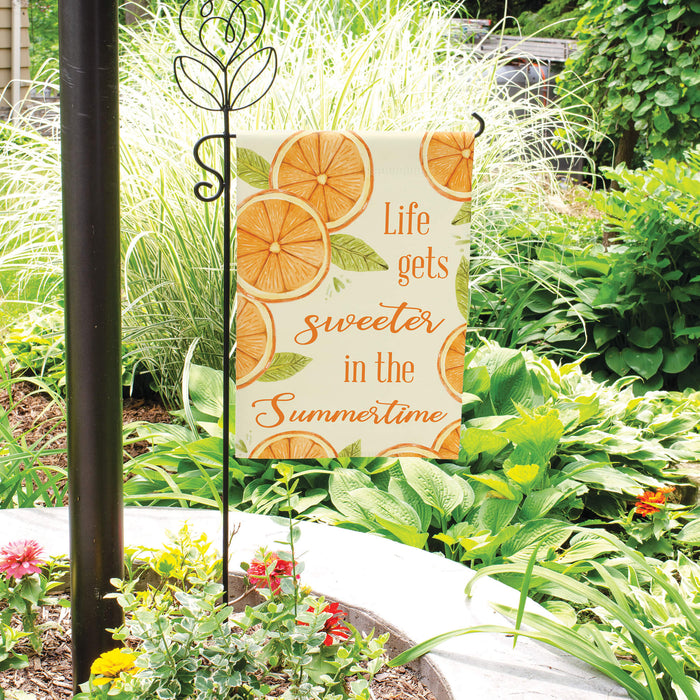Decorative garden sign with orange design and text in a garden setting