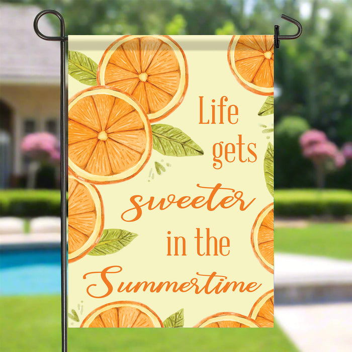 Decorative garden flag with orange slices and summer text in a backyard pool setting.