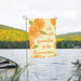 Flag with orange slices and 'Life gets sweeter in the Summertime' text in a scenic lake setting.