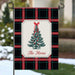 A decorative garden flag hanging from a black metal stake outdoors. The flag has a black, red, and green plaid pattern with a central cream panel showing a green Christmas tree with red ornaments and the text 'The Horns'.