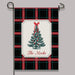 A decorative garden flag hanging from a black metal stand against a light gray background. The flag has a black, red, and green plaid pattern with a central cream label featuring a green Christmas tree illustration, red ornaments, and the text 'The Mocks'.