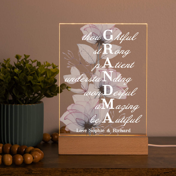 Decorative LED light with floral design and text on a wooden base, placed on a surface with a plant and beads in the background.
