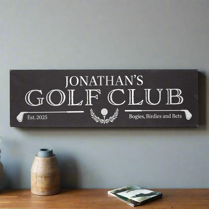 Personalized golf club sign on a wall with a vase and book in the foreground.