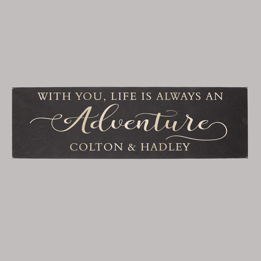 Decorative sign with text 'WITH YOU, LIFE IS ALWAYS AN ADVENTURE COLTON & HADLEY' on a gray background