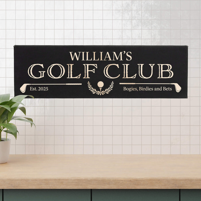 Decorative sign engraved with 'William's Golf Club' on a tiled wall with a plant and wooden countertop.