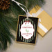 A personalized Christmas ornament displayed on a light surface with pine branches and a gift box. The ornament features a green vertical stripes and a white oval center with the text 'my first CHRISTMAS ALLIE PEYTON 2026' and a small green footprint graphic.