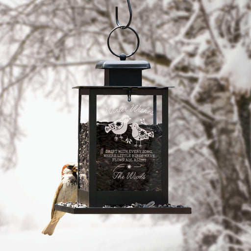 winter themed bird feeder hanging up outside in the winter with a bird perched on the back