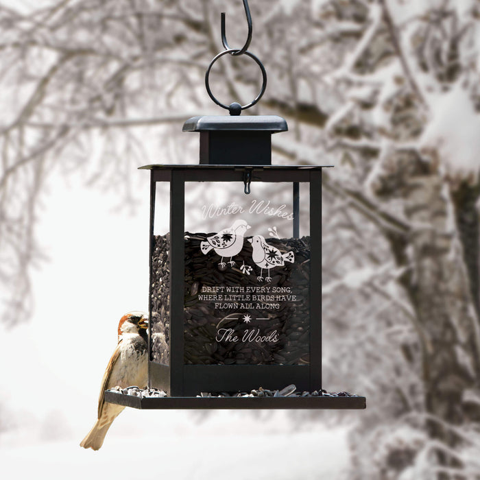 winter themed bird feeder hanging up outside in the winter with a bird perched on the back
