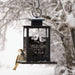 winter themed bird feeder hanging up outside in the winter with a bird perched on the back