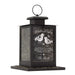 A black metal bird feeder with a hanging loop and a base filled with seed. The front panel has engraved text reading 'Winter Wishes' and 'The Shorts,' plus two bird illustrations.