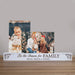 A personalized wooden Christmas photo display bar on a tabletop, featuring two printed holiday family photos stacked above custom text that reads 'Tis the Season for FAMILY' and 'BRIAN, KELLIE & JOHNNY'. The sign itself is white with dark brown engraved lettering and small decorative ornament motifs at the corners.