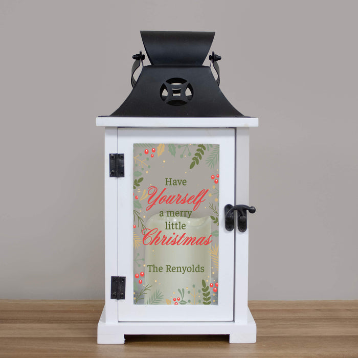 white wood lantern with a black metal top printed with a festive design that says 'Have yourself a merry little Christmas' and is personalized with a family's last name