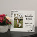 Personalized destination wedding photo frame with a couple's picture and text on a table with flowers.