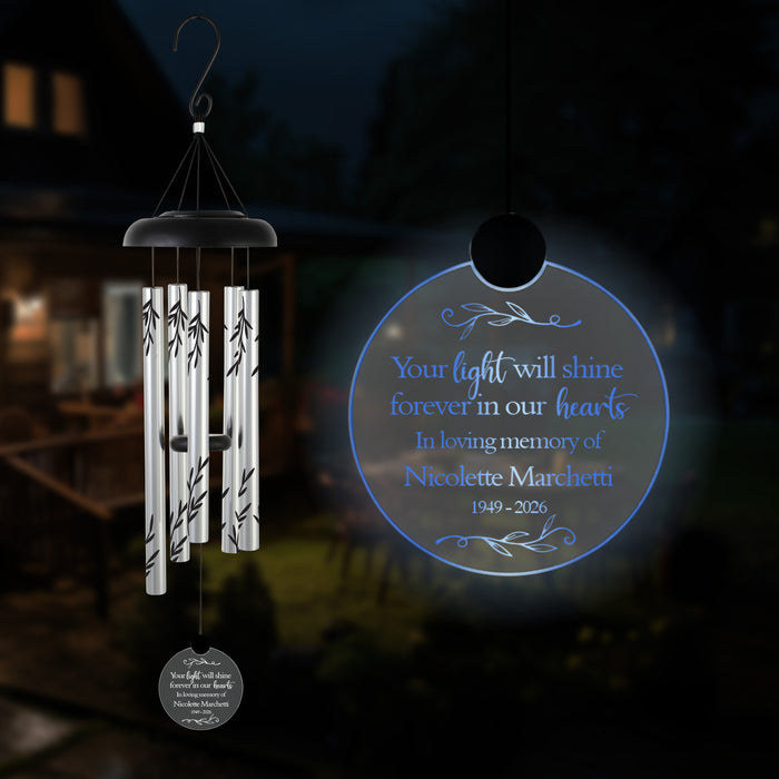 memorial custom solar wind chime with name and years of life hanging outside in the dark