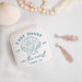 White jewelry box with shell design and text on a light background with decorative items.