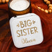 travel sized white jewelry box with 'BIG SISTER' text next to a candle on a wooden surface.