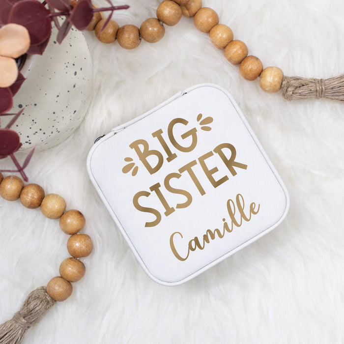 Small white jewelry box with 'Big Sister' text on a light background with wooden beads.